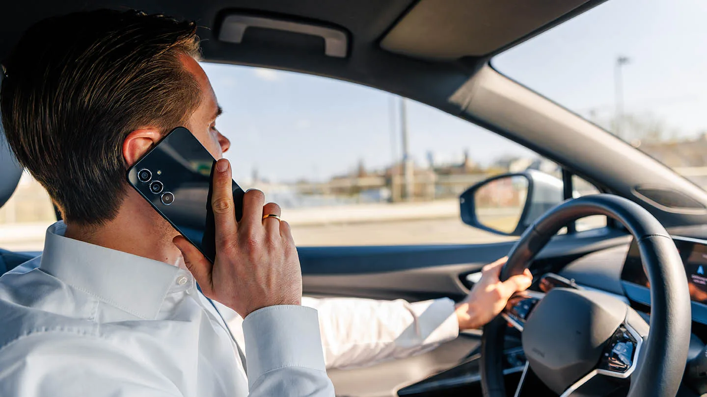 Mann mit Handy am Steuer