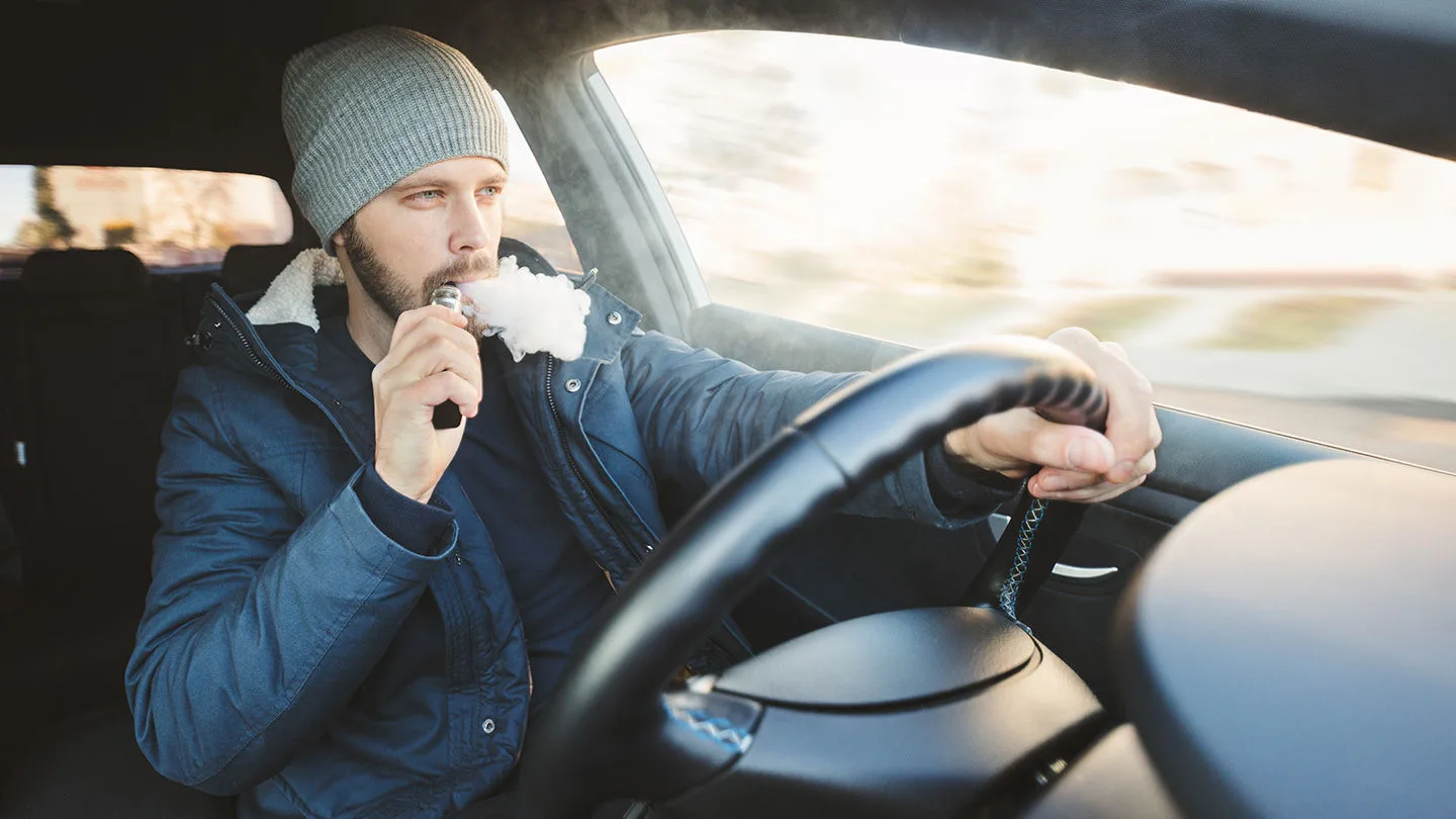Mann raucht E-Zigarette im Auto