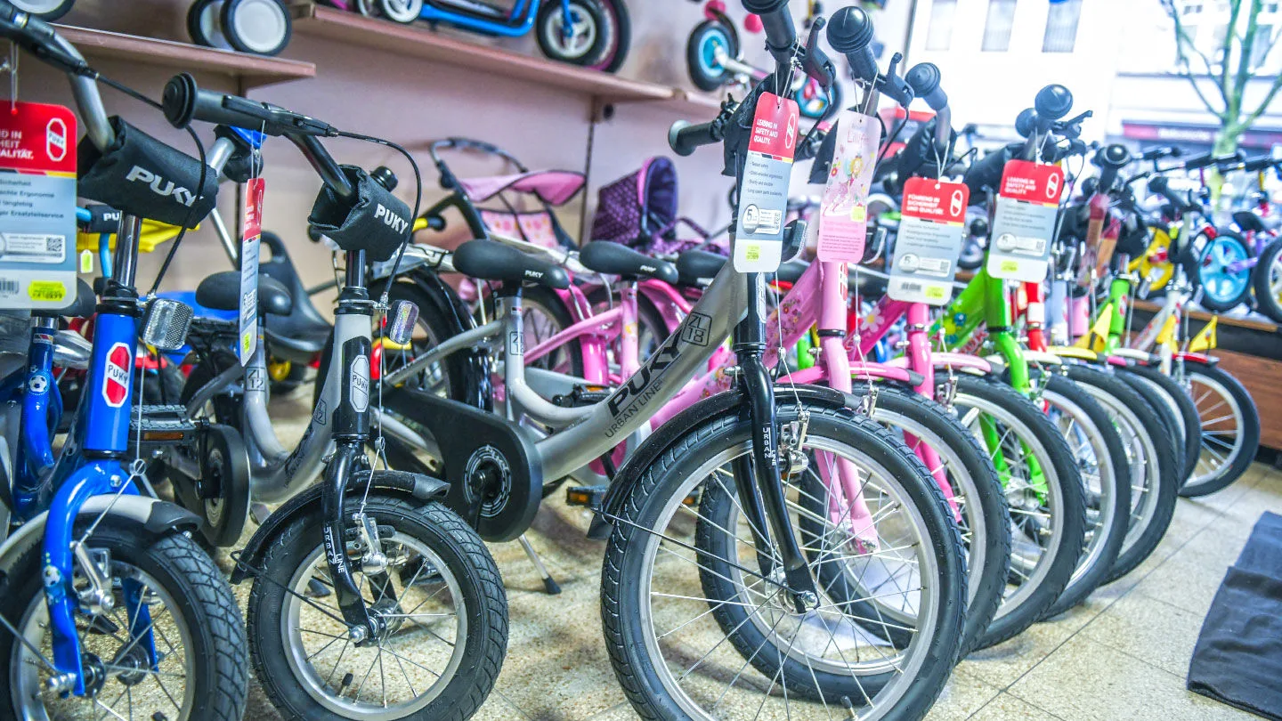 Mehrere Kinderfahrräder stehen in einem Fahrradgeschäft nebeneinander. Die Modelle sind in unterschiedlichen Farben und Größen ausgestellt.