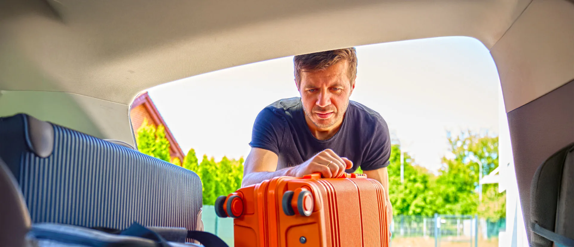 Mann stellt einen Koffer ins Auto