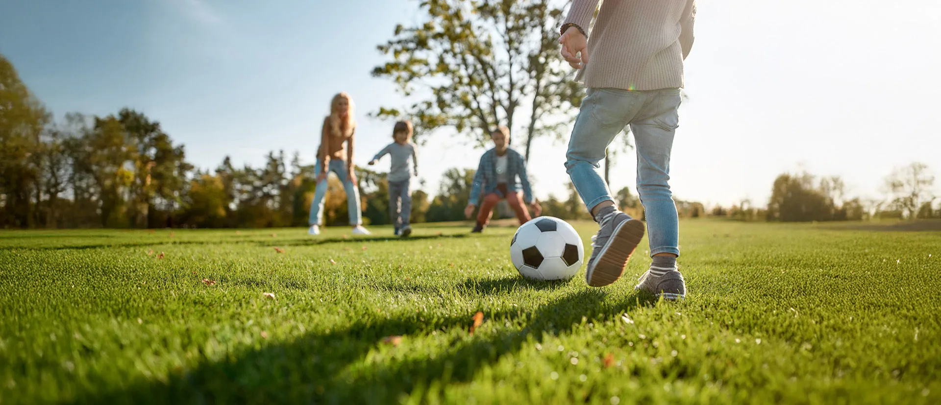 Junges Mädchen spielt Fußball im Park mit ihren Freunden.