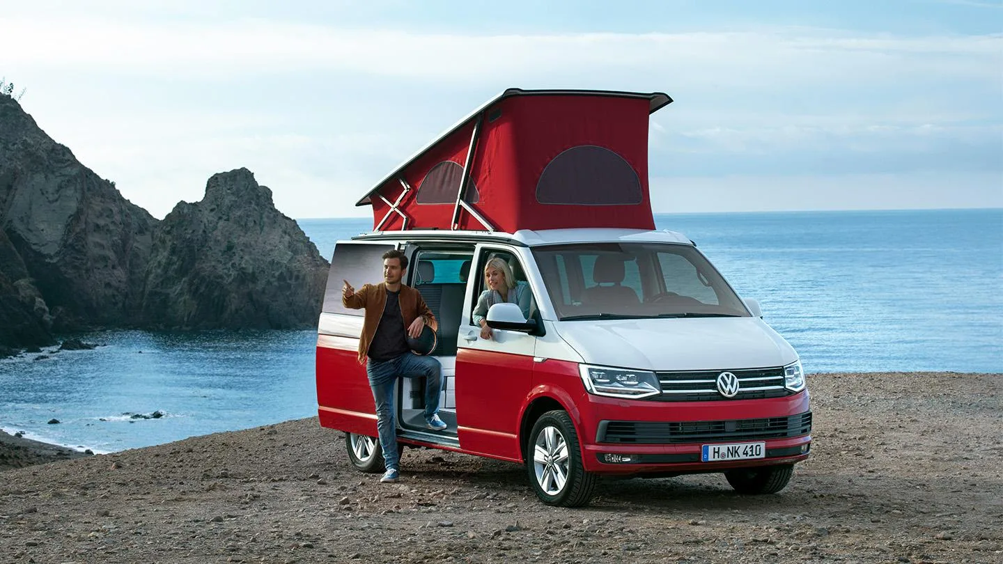 Camper Van mit Dachzelt mit Meer im Hintergrund 