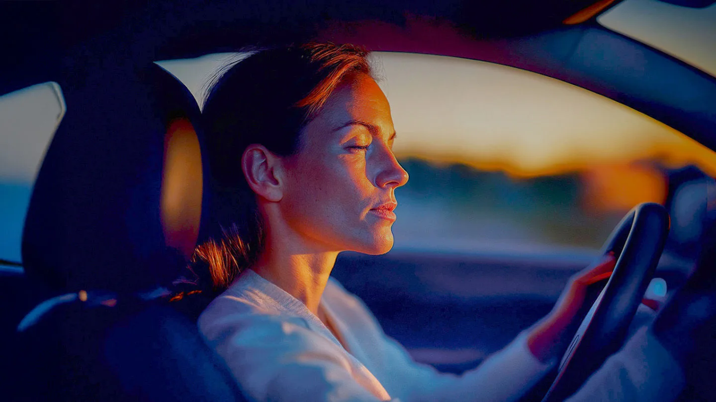 Eine Frau im Auto am Steuer mit geschlossenen Augen