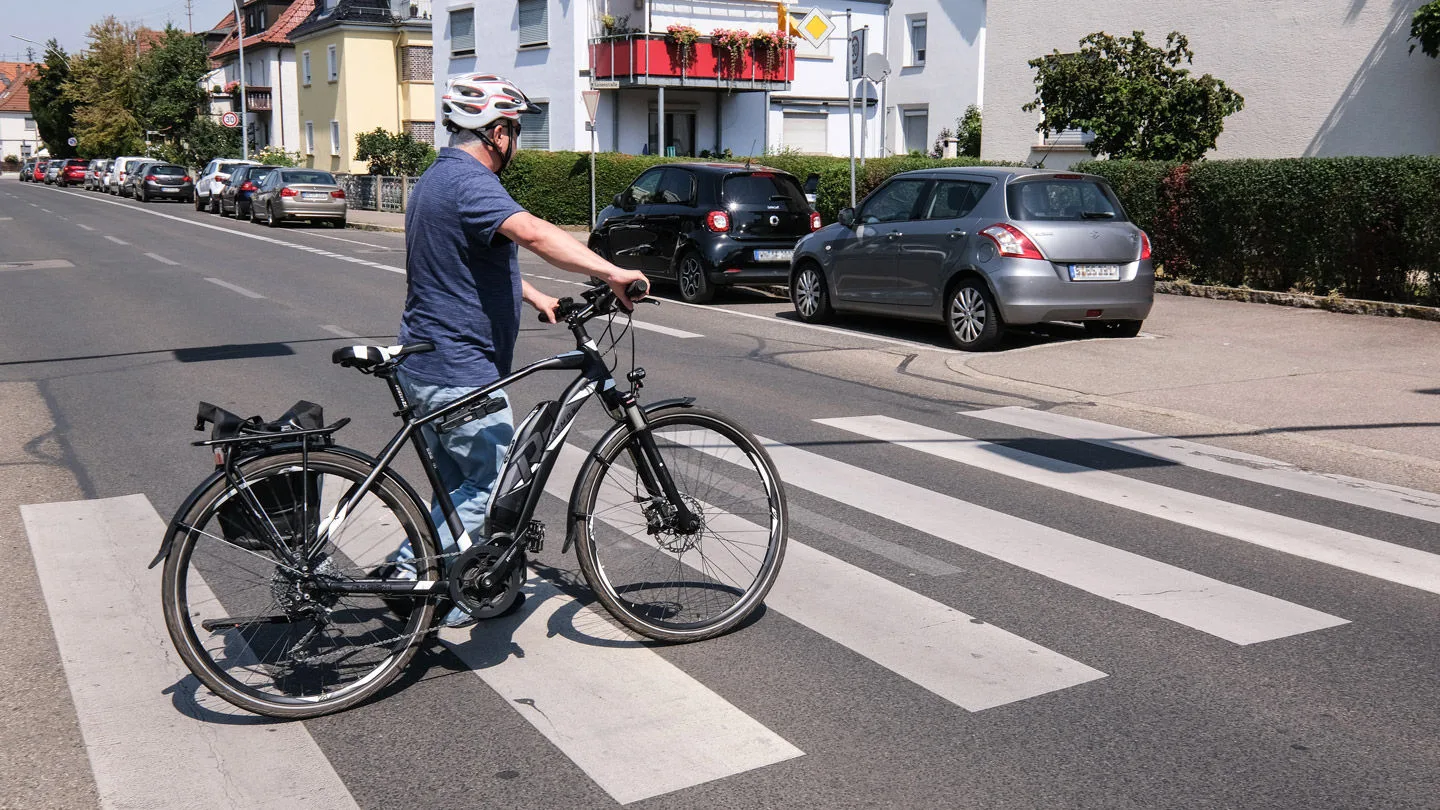 Radfahrer schiebt sein Fahrrad über einen Zebrastreifen