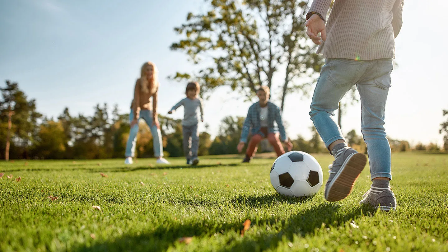 Junges Mädchen spielt Fußball im Park mit ihren Freunden.