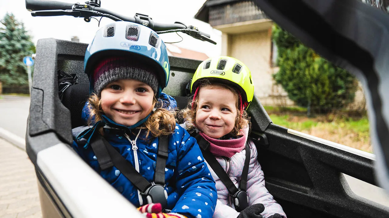 Zwei Kinder sitzen in einem Lastenrad
