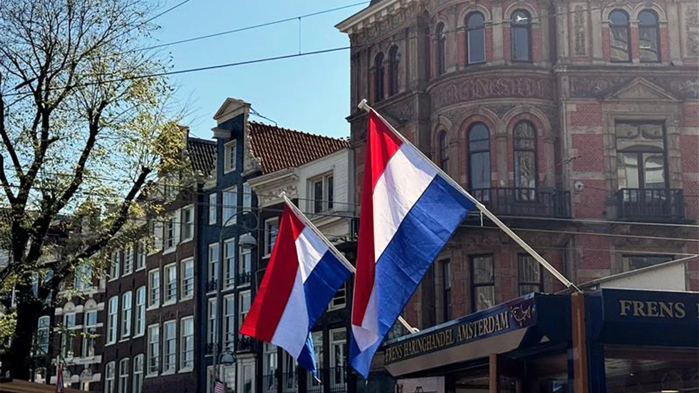 Niederländische Flaggen an einem Fahnenmast vor anderen Gebäuden 