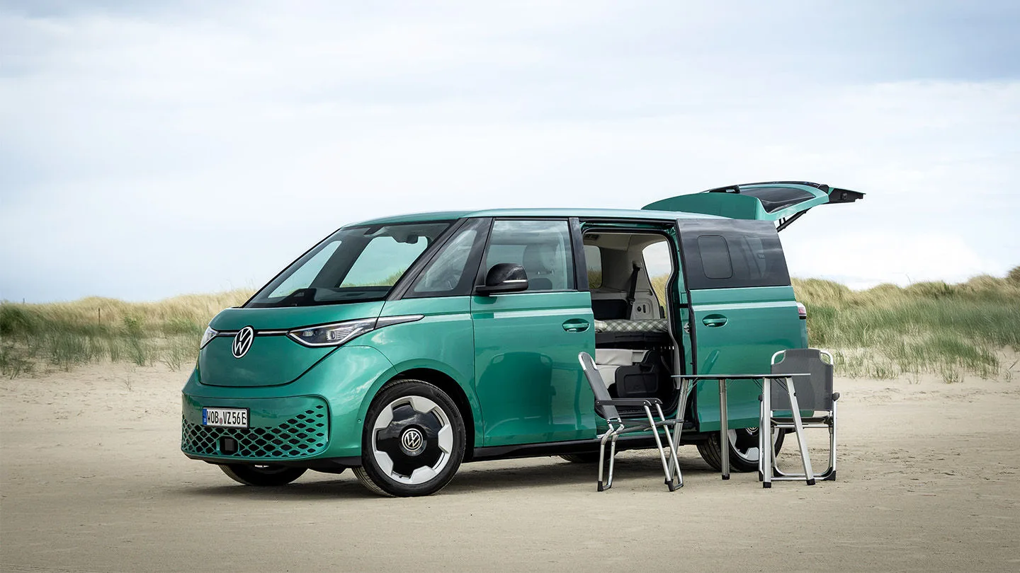türkisfarbener Campervan von VW steht im Sand