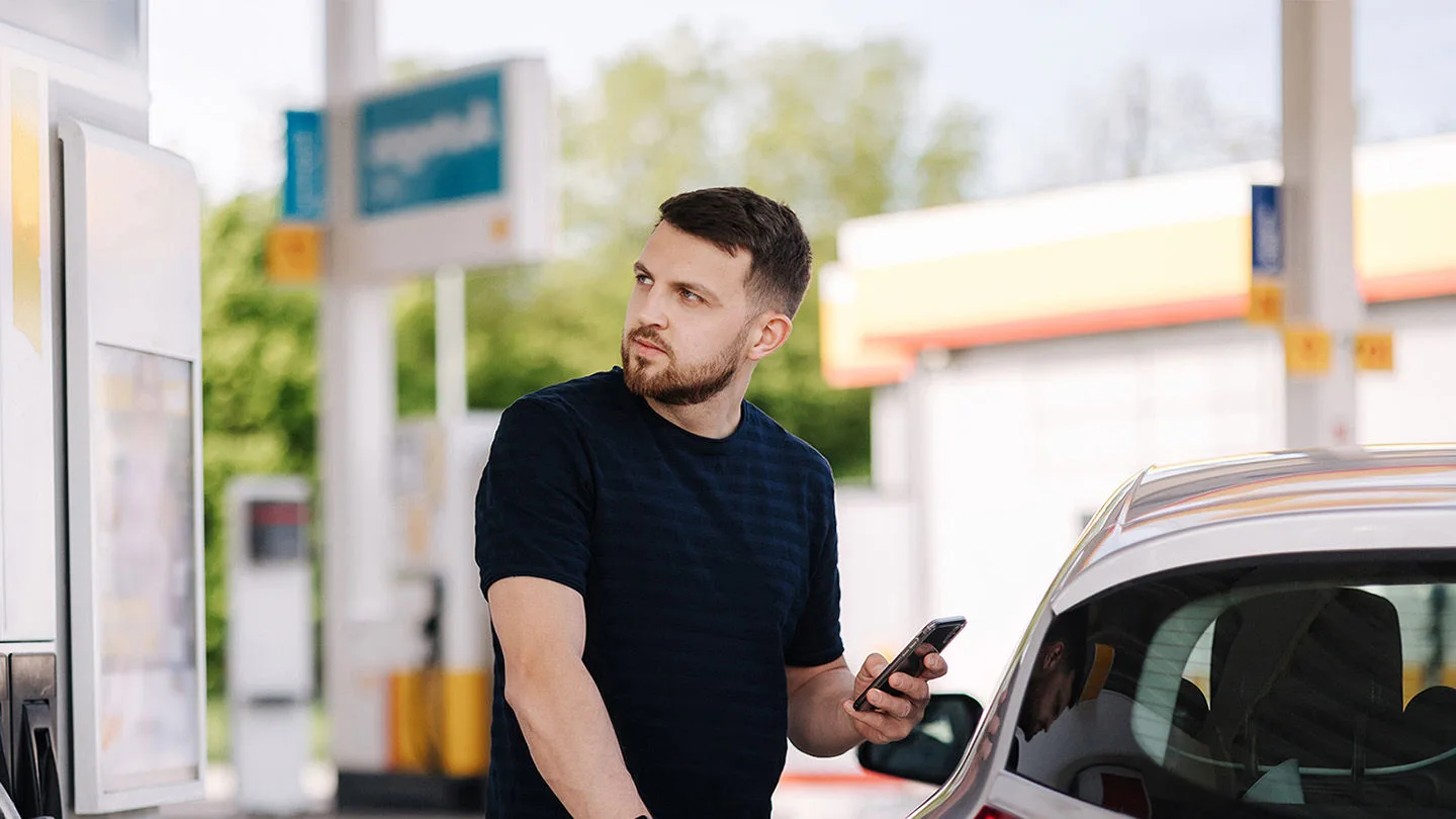 Mann steht an einer Zapfsäule