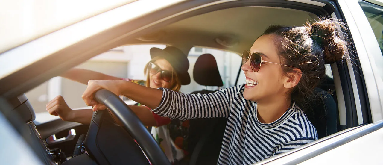 Frau lachend am Steuer eines Autos