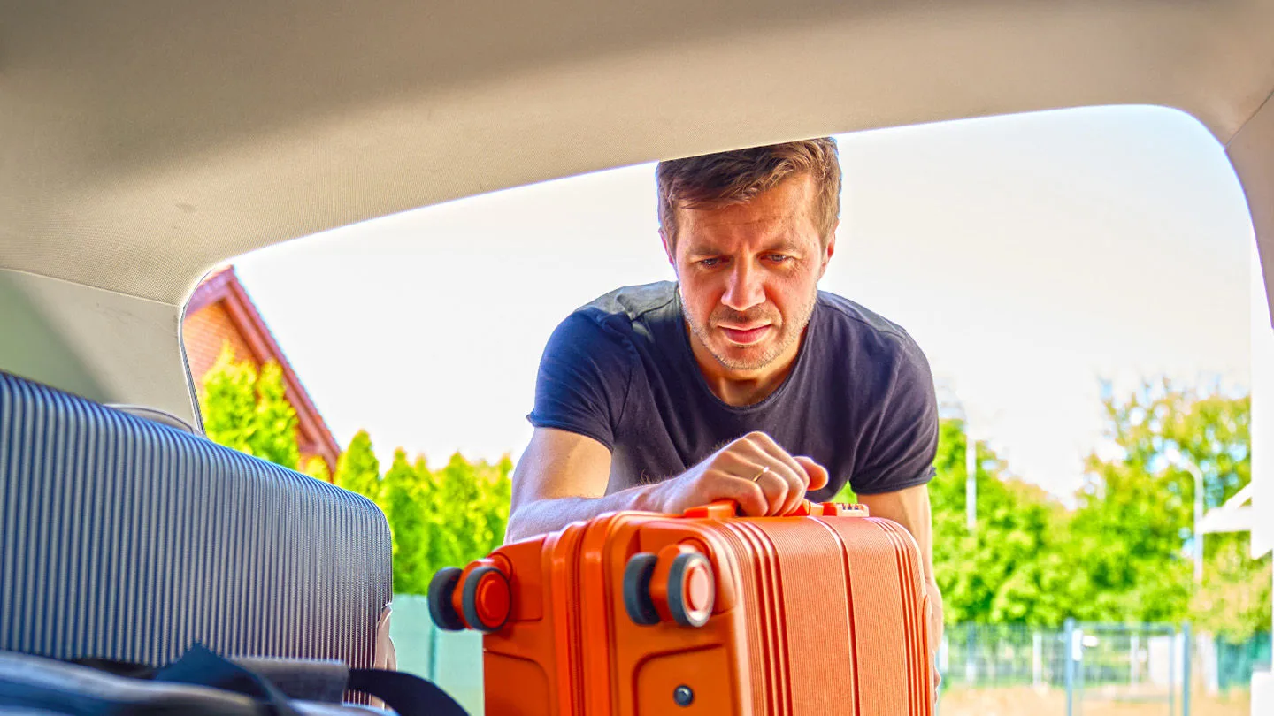 Mann stellt einen Koffer ins Auto