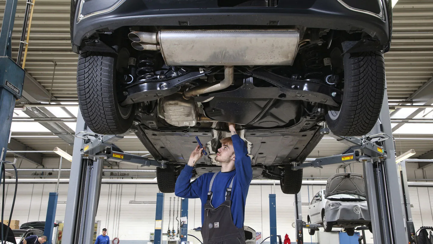 Ein Mann repariert ein Auto auf einer Hebebühne in einer Werkstatt