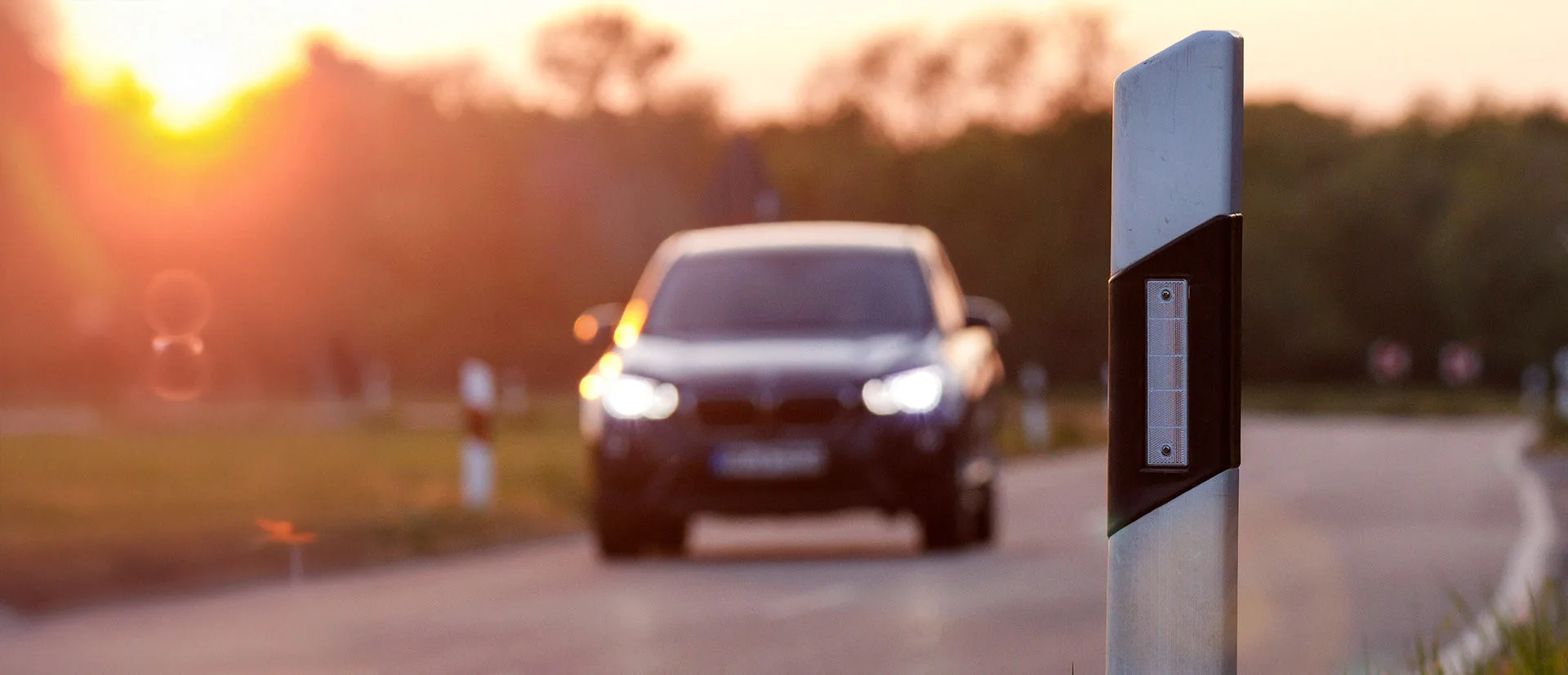 Bild eines Leitpfostens aus der Nähe im Hintergrund ist ein Auto zu sehen