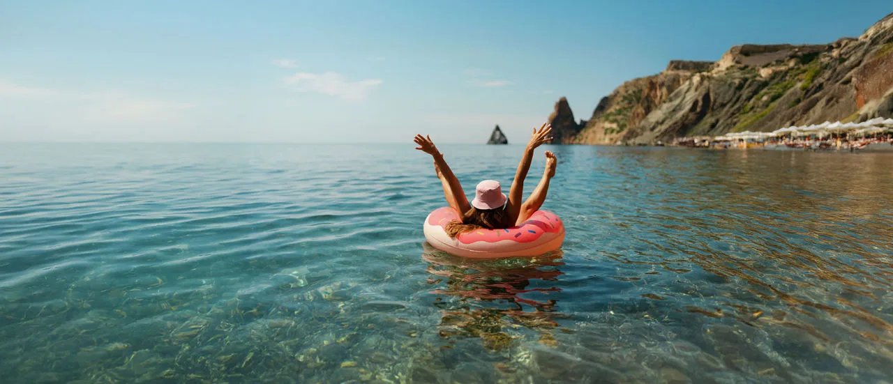 Eine Frau lässt sich im Urlaub im Meer in einem Schwimmreifen treiben.