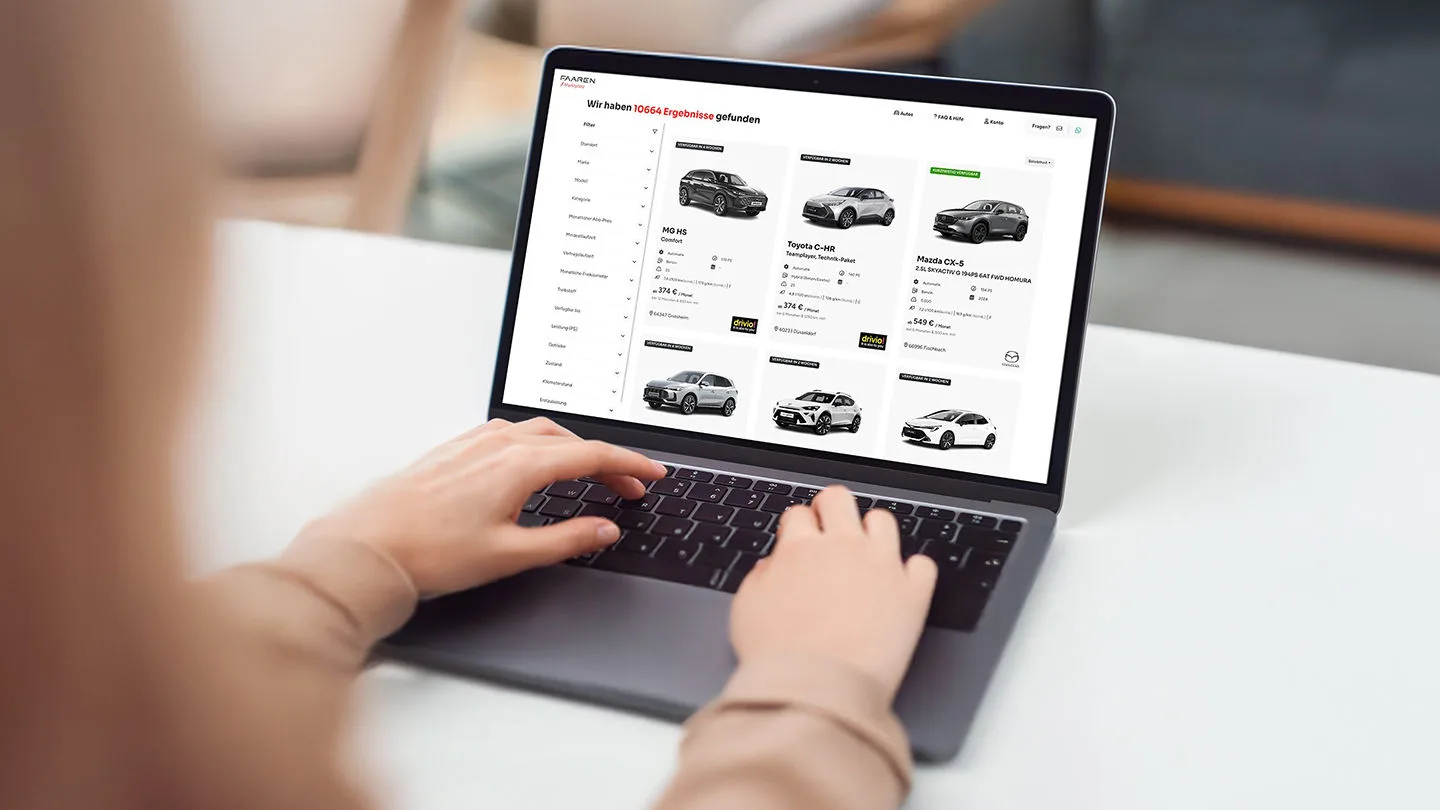 Eine Frau sieht sich am Laptop die Auswahl an Autos zum Auto-Abo an.