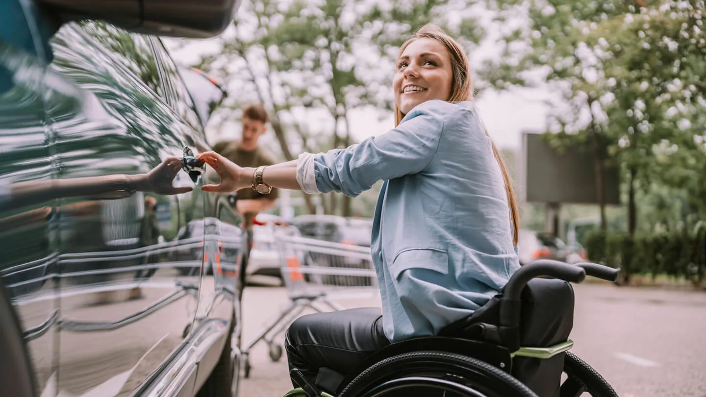 Frau im Rollstuhl öffnet ein Auto