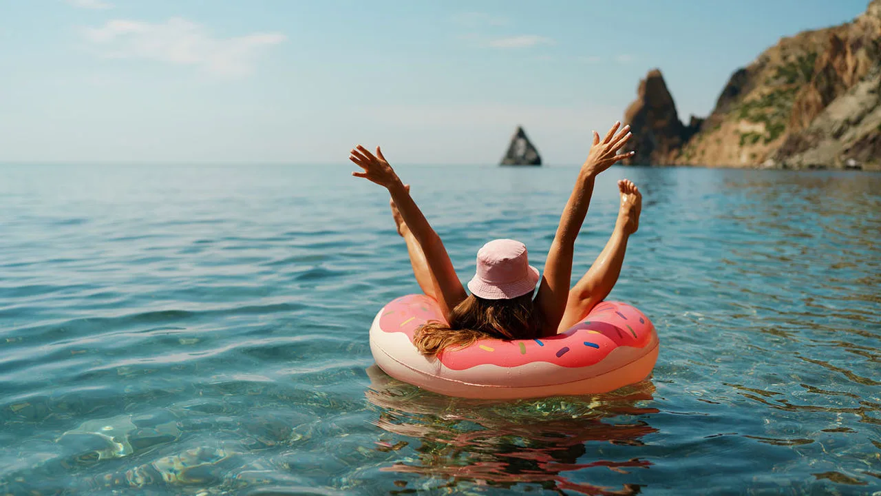 Eine Frau lässt sich im Urlaub im Meer in einem Schwimmreifen treiben.