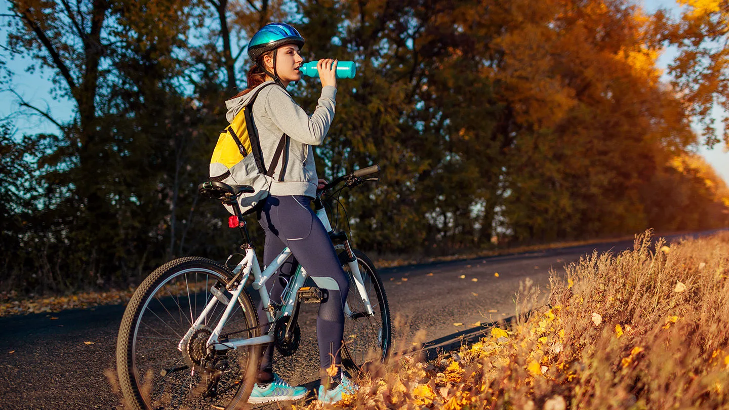 Eine Fahrradfahrerin, die eine Trinkpause macht