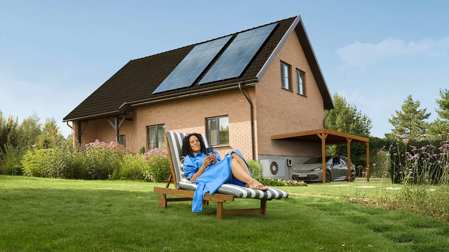 Eine Frau entspannt auf der Liege vor ihrem Haus weil wie Strom von der EnBW hat.
