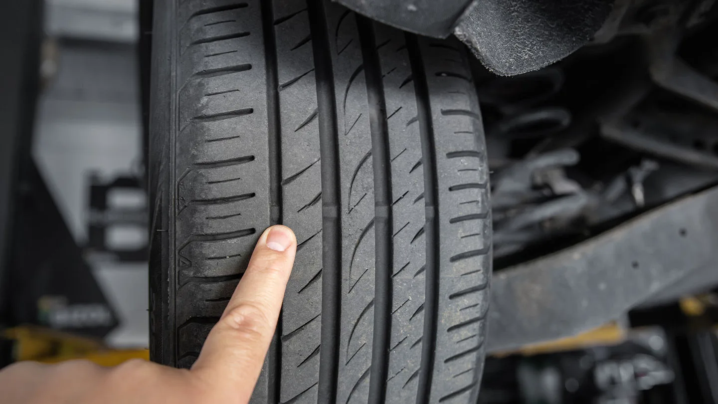 Finger zeigt auf Reifenprofil