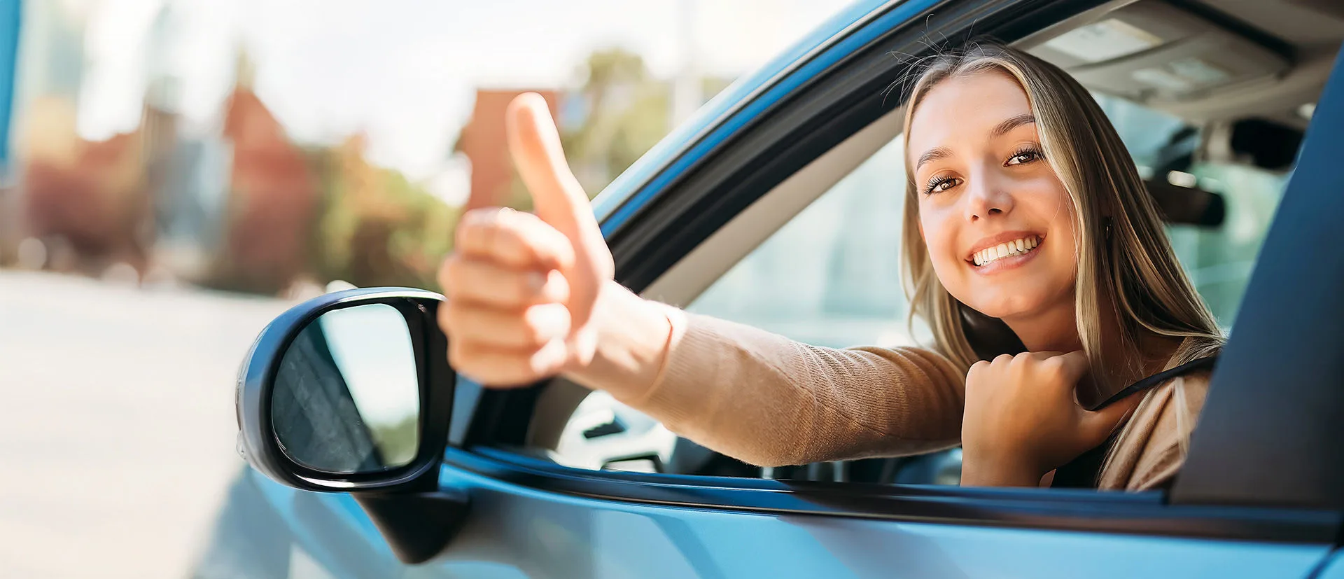 Eine junge Frau im Auto, die den Daumen hoch zeigt neuen Führerscheinregeln der EU