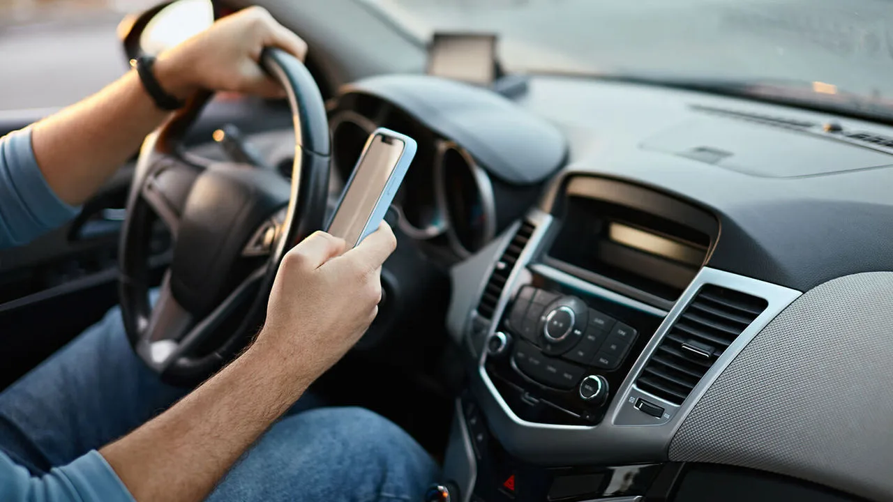Autofahrer sitzt mit Handy am Steuer 