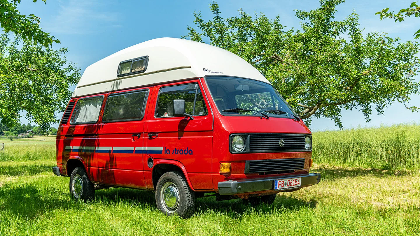 roter Campingvan steht auf dem Gras 