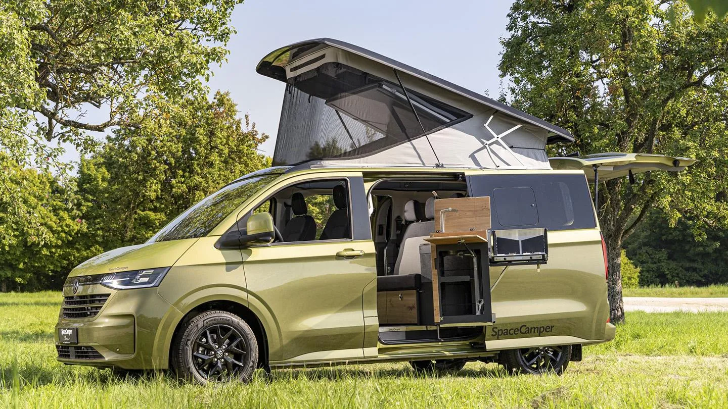 Spacecamper mit ausgefahrenem Dach steht auf einer Wiese