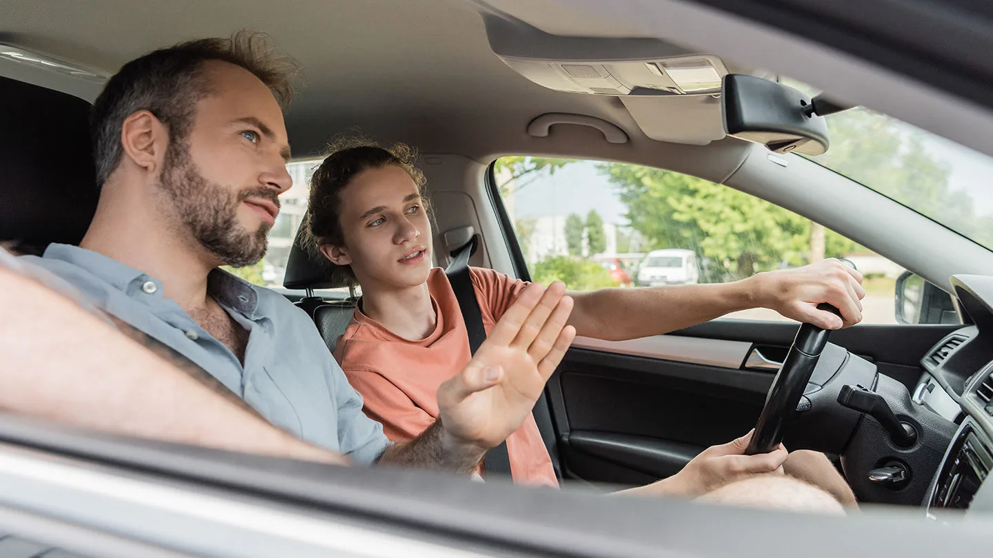 Junger Mann am Steuer, neben ihm ein erfahrener Autofahrer, der ihn beim begleitenden Fahren unterstützt