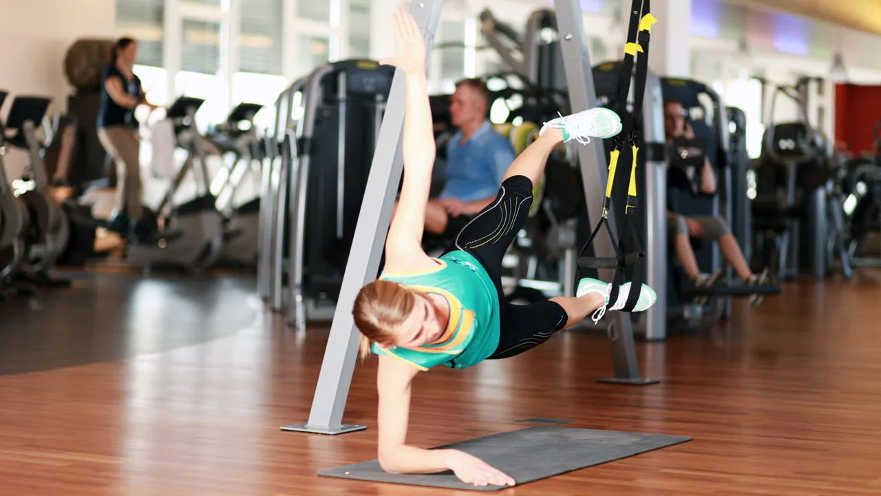 Frau im Fitnessstudio, im Hintergrund Trainingsgeräte