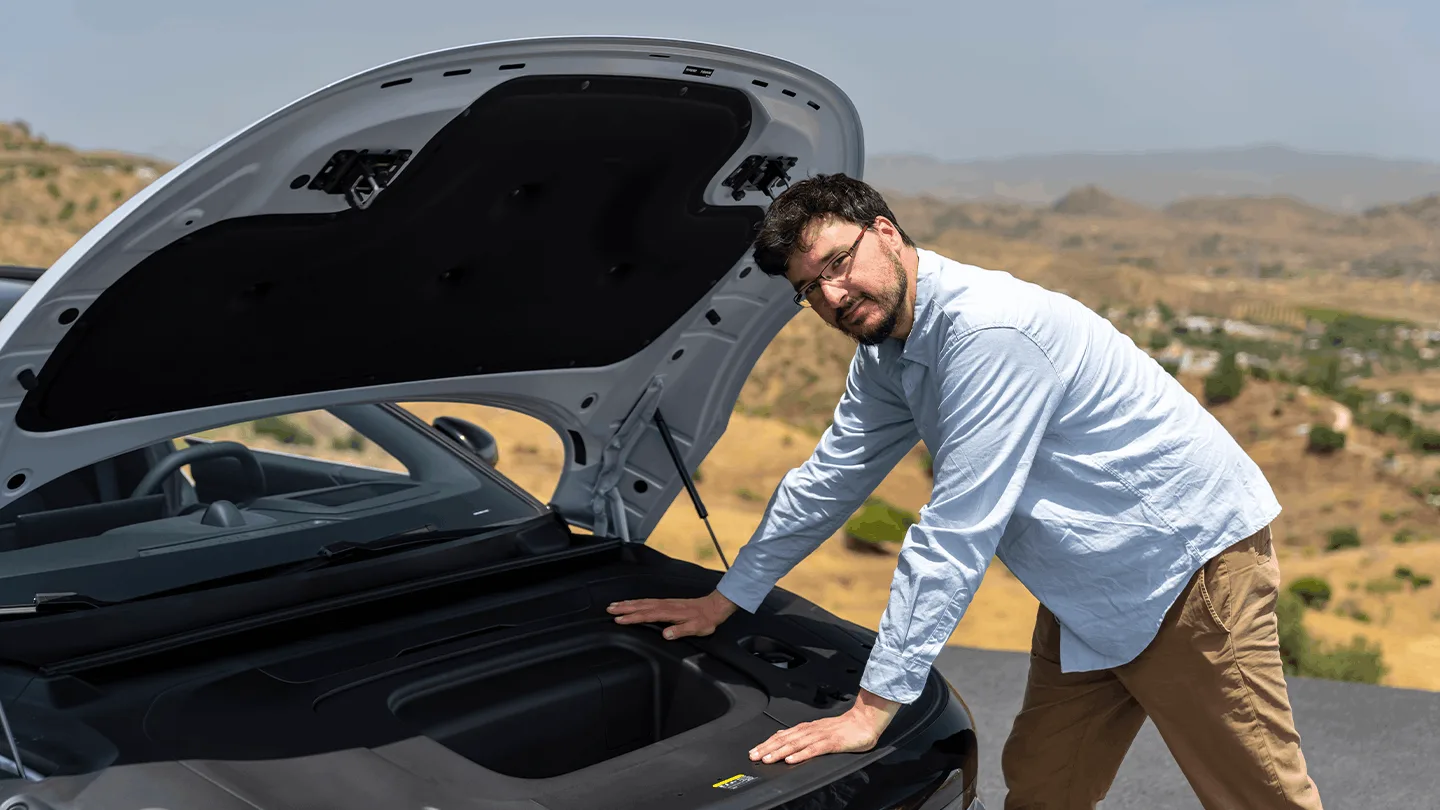 Mann zeigt den Frunk des ZEEKR 7 GT bei geöffneter Haube vor bergiger Landschaft