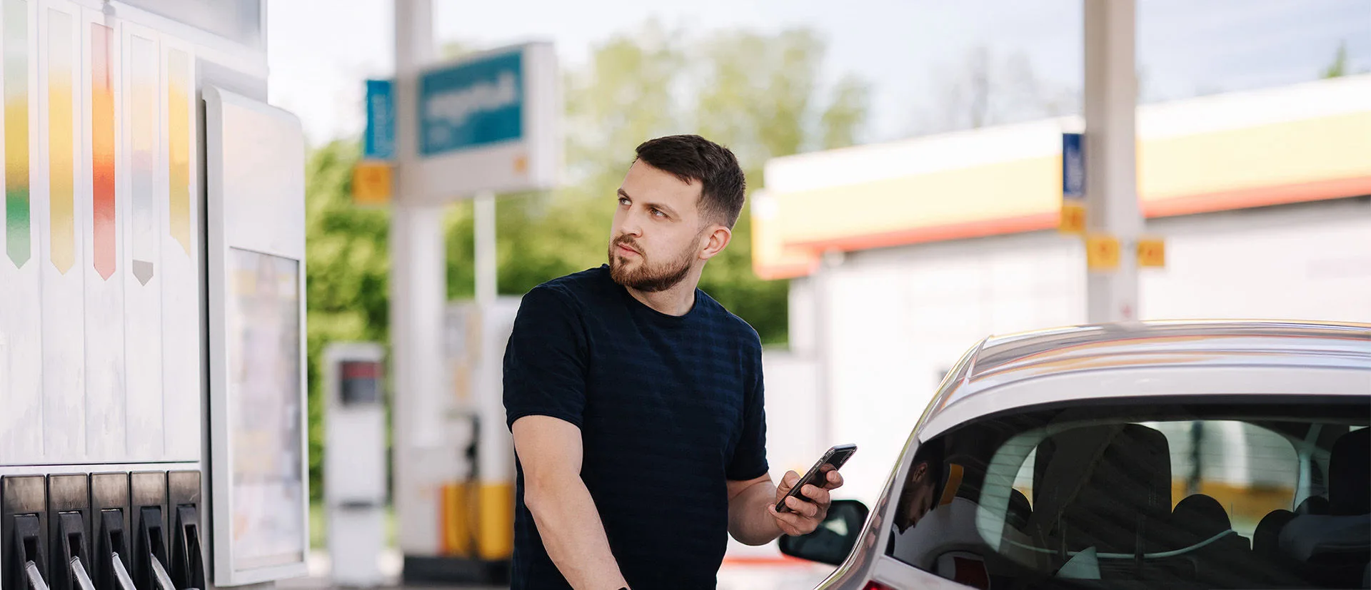 Ein Mann steht an einer Zapfsäule und schaut kritisch auf den Preis