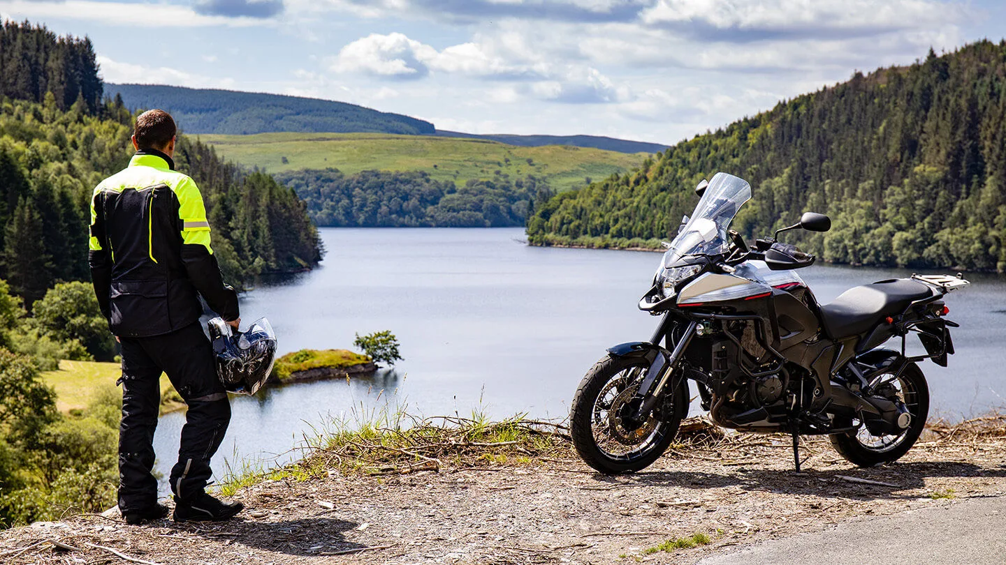 Mann vor einem See in einer Motorad-Regenkombination