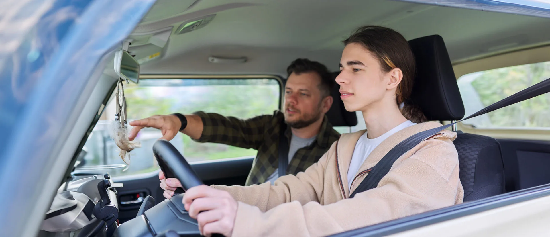 Mann erklärt jungem Fahrer, der am Steuer sitzt, das Fahren