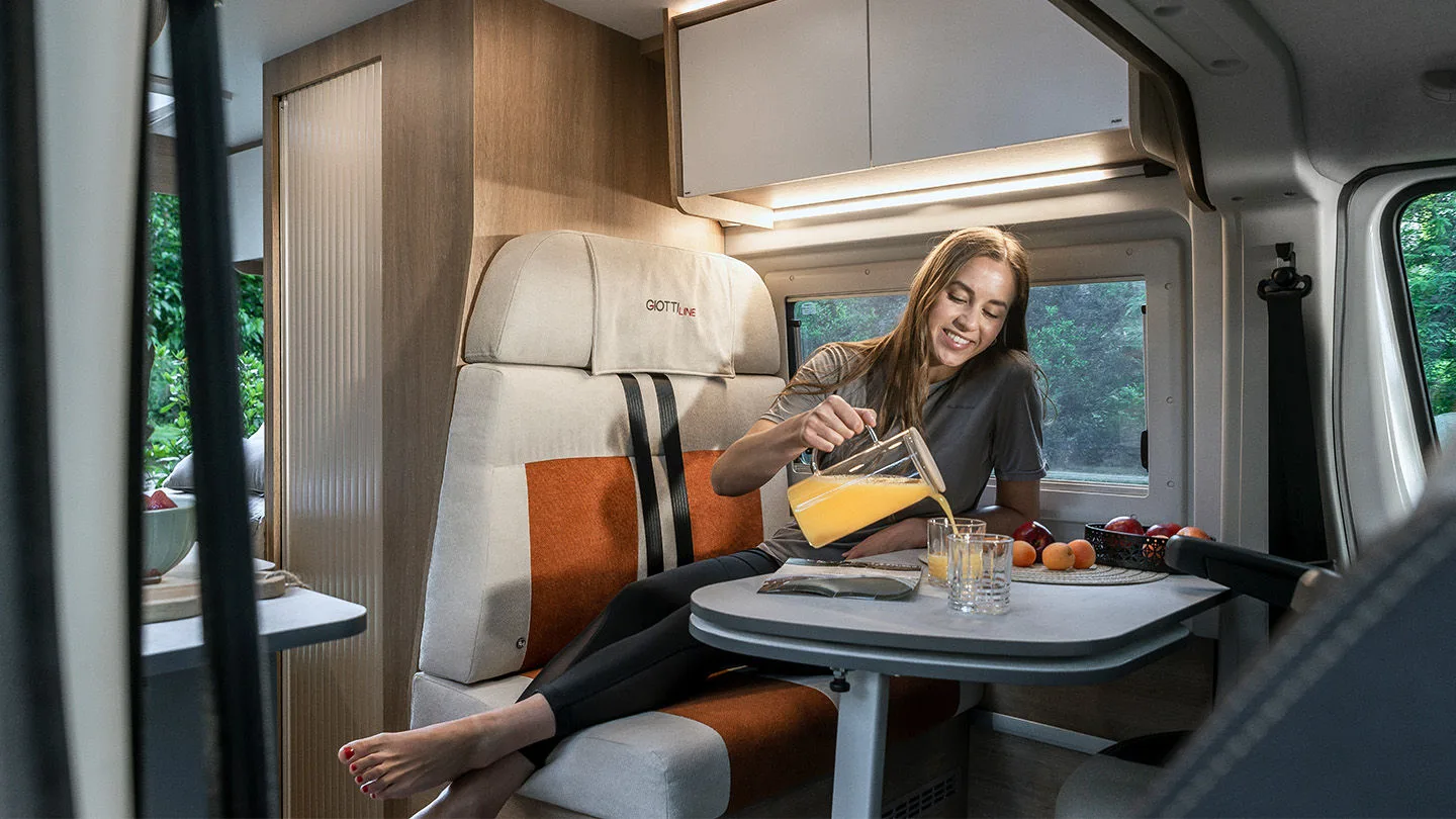 Frau mit Weinglas sitzt in einem Camper