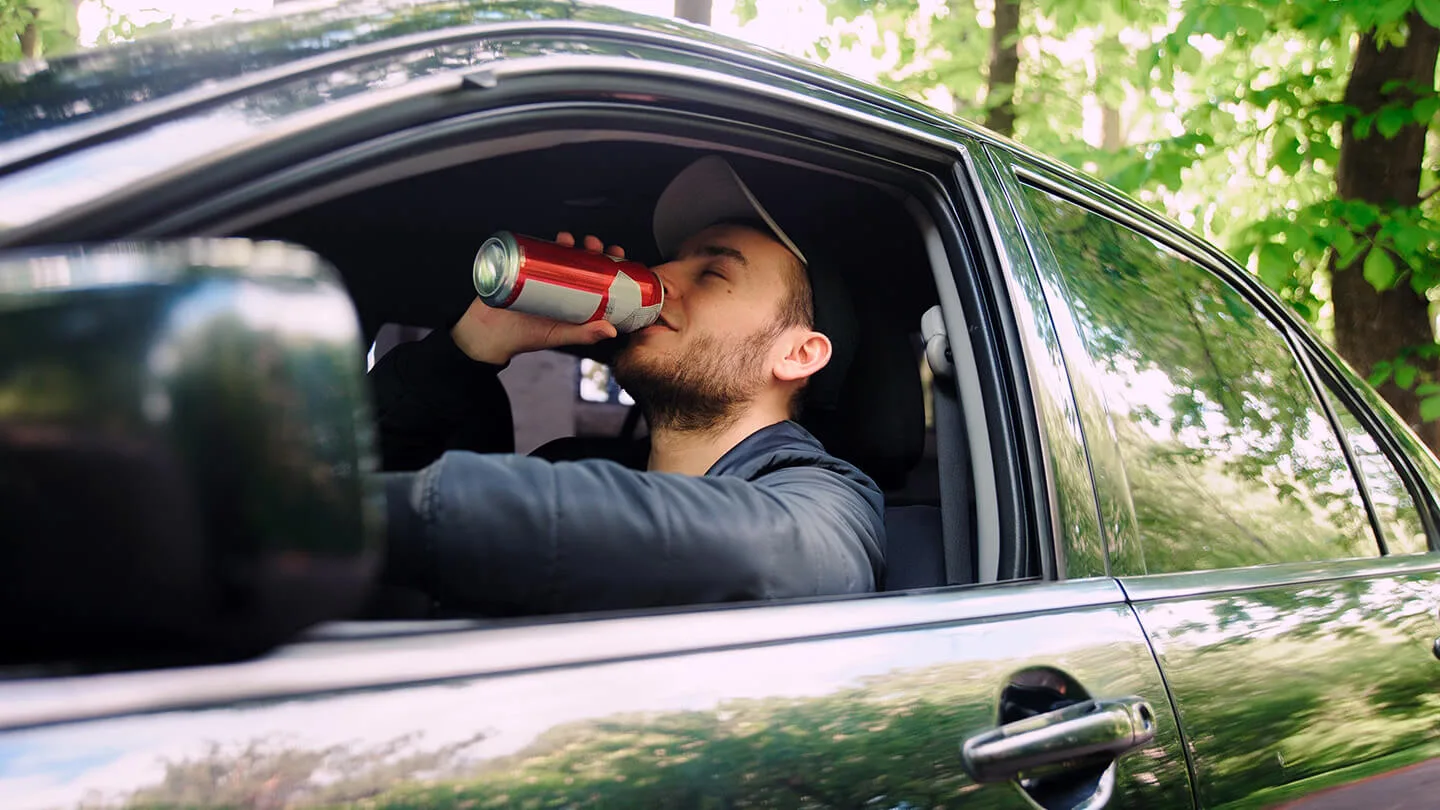 Mann mit Bierdose am Steuer eines Autos