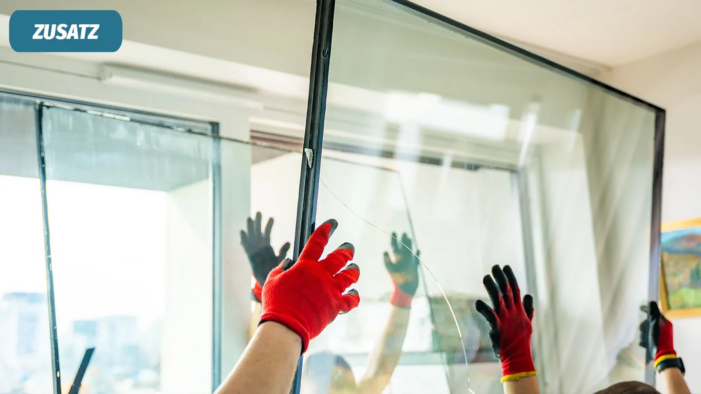 Handwerker setzen eine neue Glasscheibe ein ein Fenster ein.