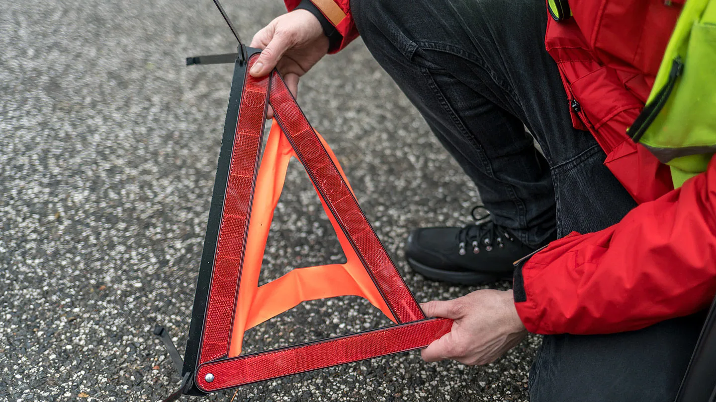 Ein Mann baut ein Warndreieck zusammen