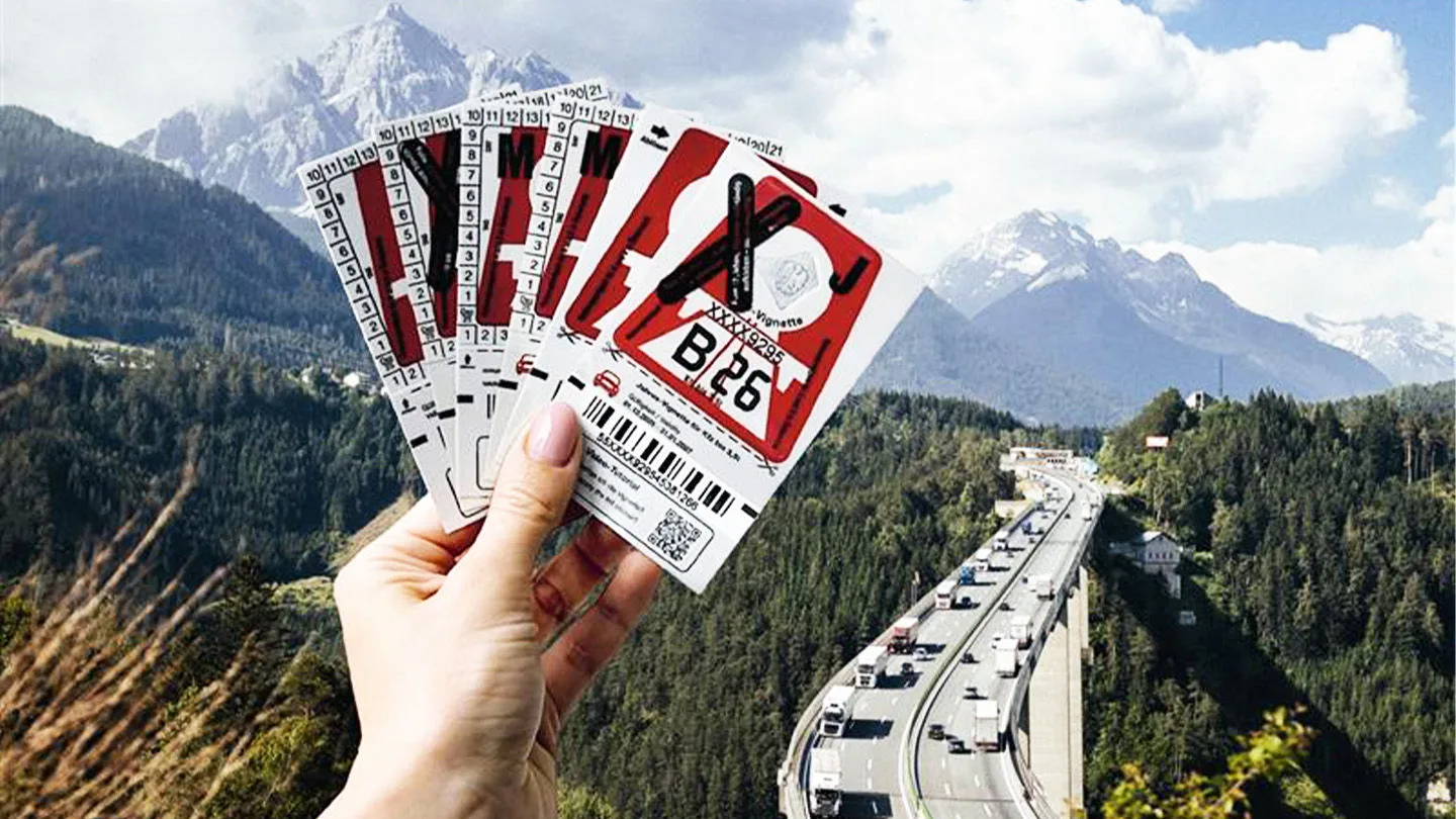 Vignettenfächer in einer Hand vor Alpenlandschaft und Autobahn